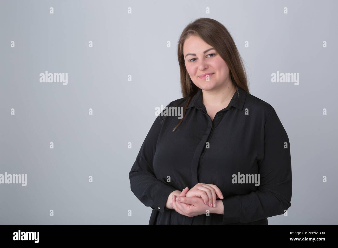 Donna allegra e di dimensioni più in camicia nera casual in posa in studio. Ritratto di amichevole donna sovrappeso bianco Foto Stock