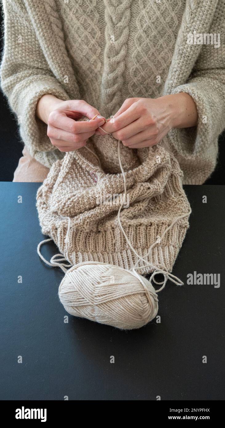 Mani femminili che si lavorano a maglia in COSE-up. Ragazza che si rilassa a lavorare a maglia un caldo maglione. Foto Stock