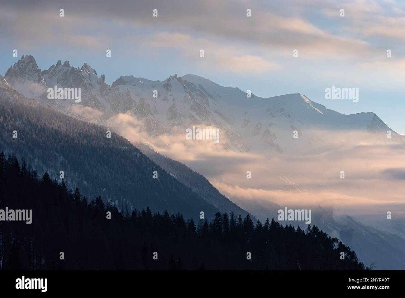 Strati di montagna che formano parti del massiccio del Monte Bianco con fogli di nuvole al tramonto invernale a Chamonix, Francia Foto Stock