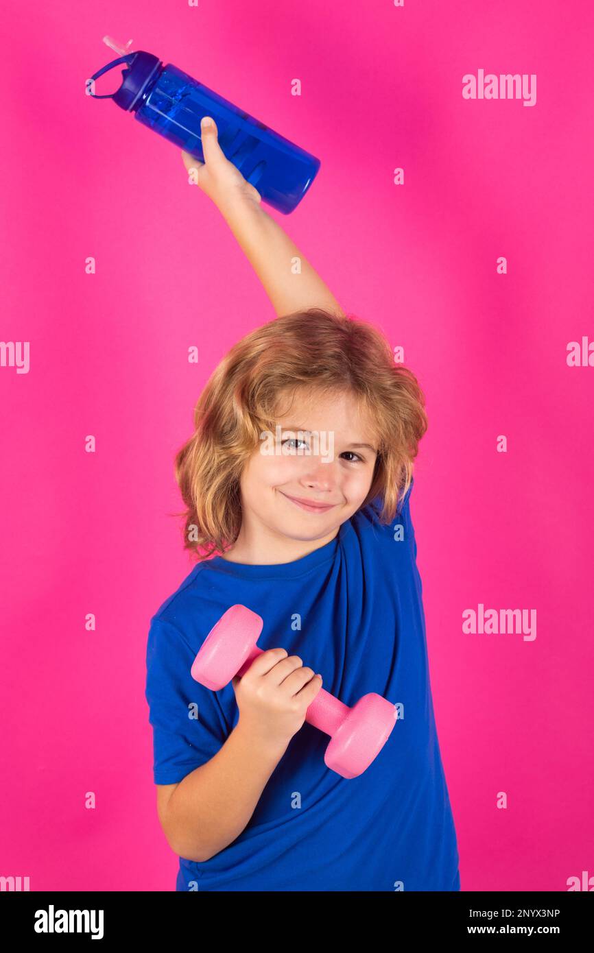 Bambini sportivi, studio isolato ritratto su sfondo rosa rosso. Capretto che alza un dumbbell. Allenamento per bambini carino con manubri. Fitness per bambini. Esercizio del ragazzo Foto Stock