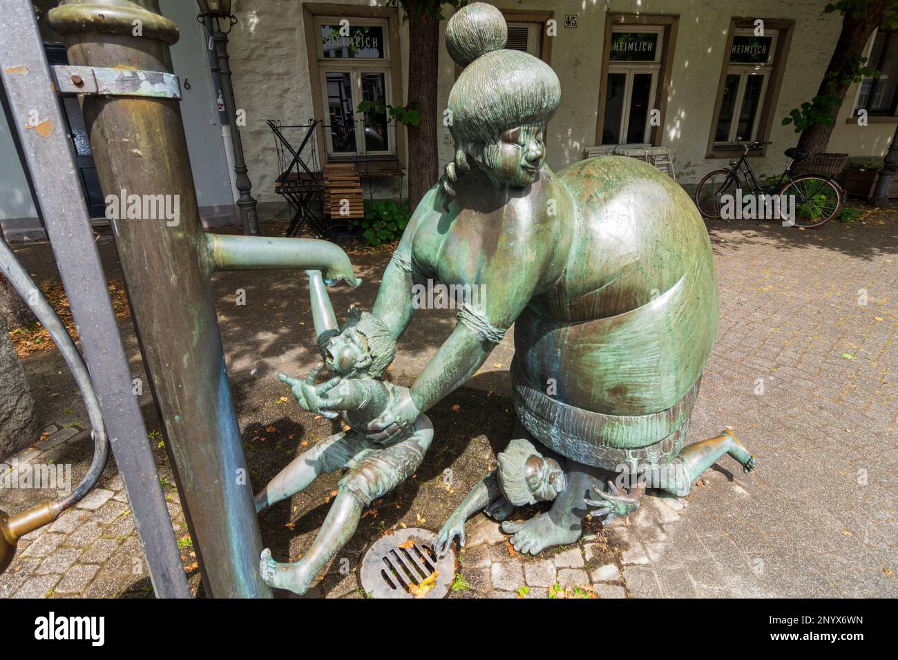 Osnabrück: Scultura la fontana della pompa o la donna di lavaggio. Scultura in bronzo di una donna grassa che lava un bambino sotto una pompa, un secondo bambino è tenuto sotto Foto Stock
