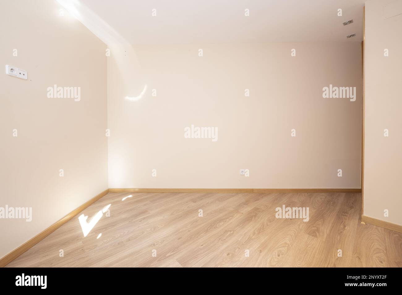 Soggiorno vuoto di una casa con pavimento in legno galleggiante con pareti color crema Foto Stock
