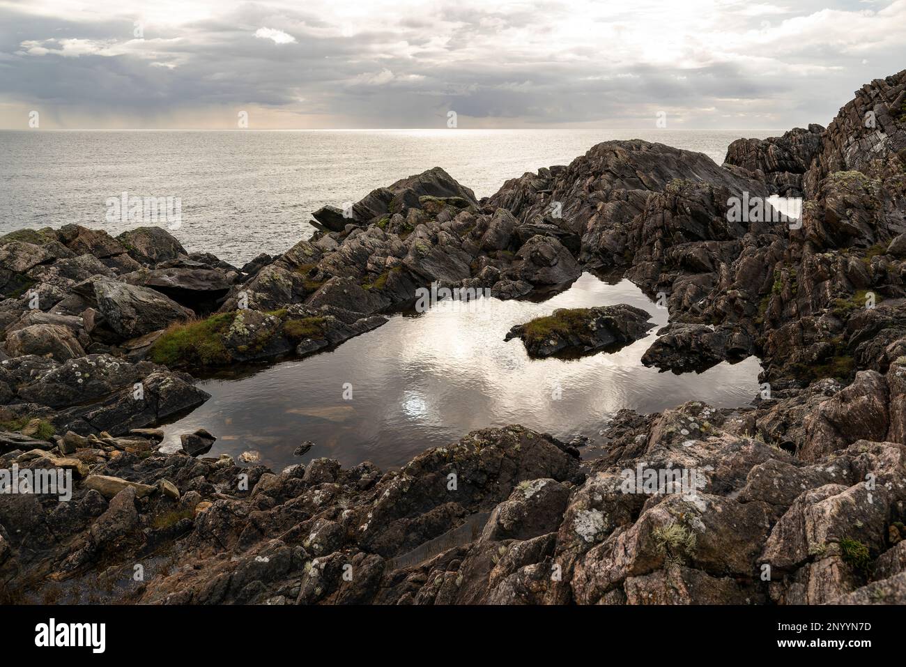 Il cielo drammatico si riflette in una piscina rocciosa a Annagh Head, la penisola di Mullet, County Mayo, Irlanda Foto Stock