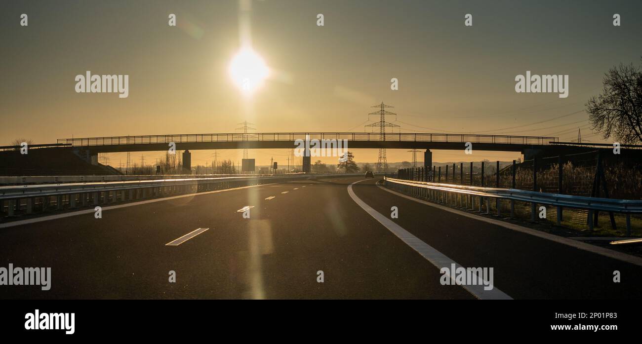Guida al sole a un Autobahn tedesco. Simbolo per il pericolo di guardare alla luce solare durante la guida. Foto Stock