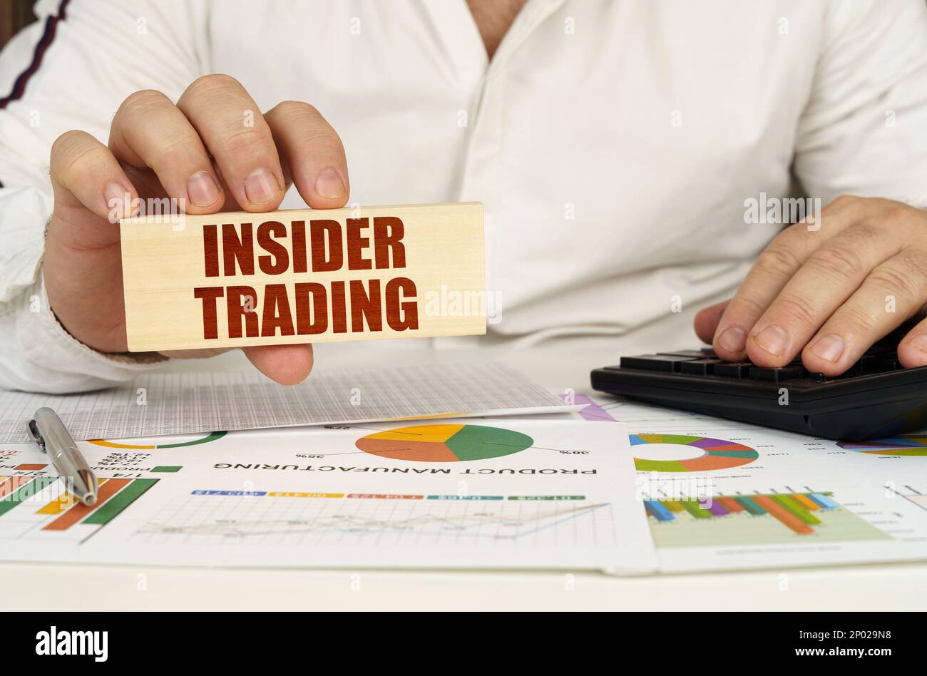 Concetto aziendale. Sulla tabella sono le tabelle di affari e i diagrammi nelle mani di un blocco di legno con l'iscrizione - insider trading Foto Stock