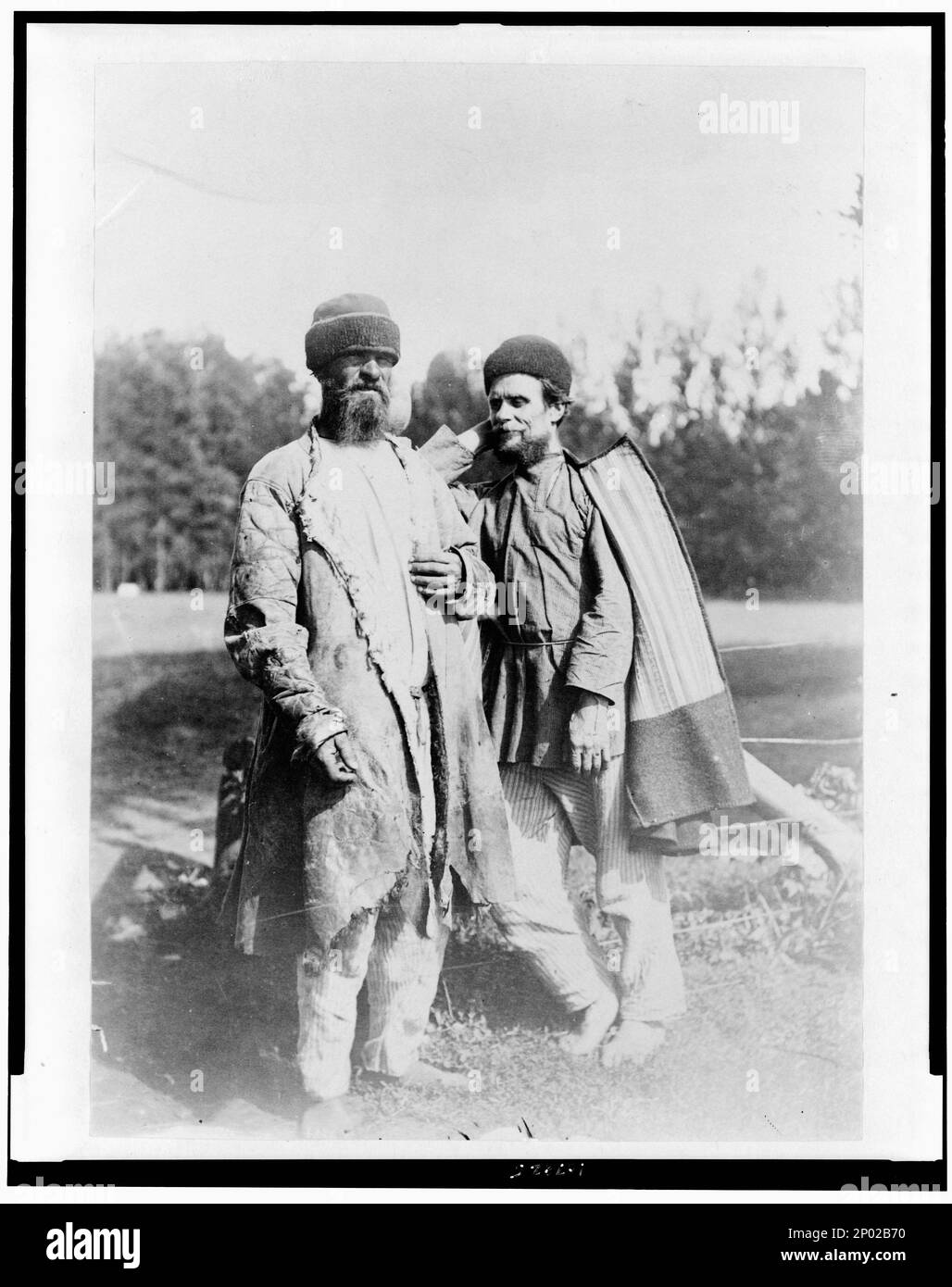 Due uomini in piedi, all'aperto, a tutta lunghezza, Russia. Frank and Frances Carpenter Collection, prigionieri,Russia,1880-1930, uniformi carcerarie,Russia,1880-1930. Foto Stock