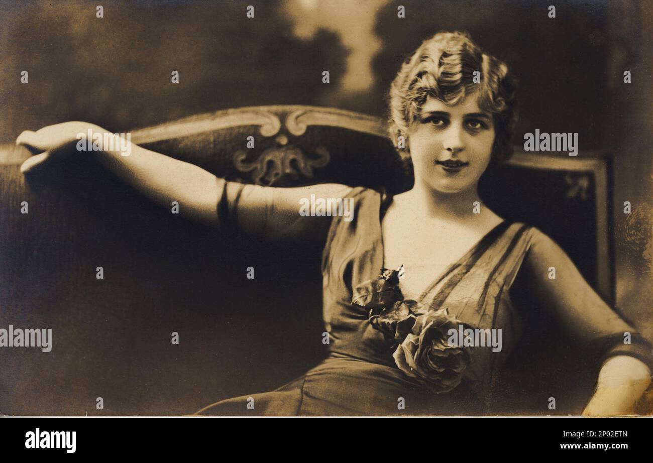 1915 ca. , ITALIA o FRANCIA : Una bellezza perfetta , cartolina italiana dagli anni 20 . - RAGAZZA - BELLEZZA - MODA - foto di moda - cartolina - fiori - fiori - fiori - rosa - rosa - sorriso - sorriso - DONNA - DONNA - BELLE EPOQUE - scollatura - scollo - decolleté - sofà - divano - divano - rosa rosa - rose ----- Archivio GBB Foto Stock