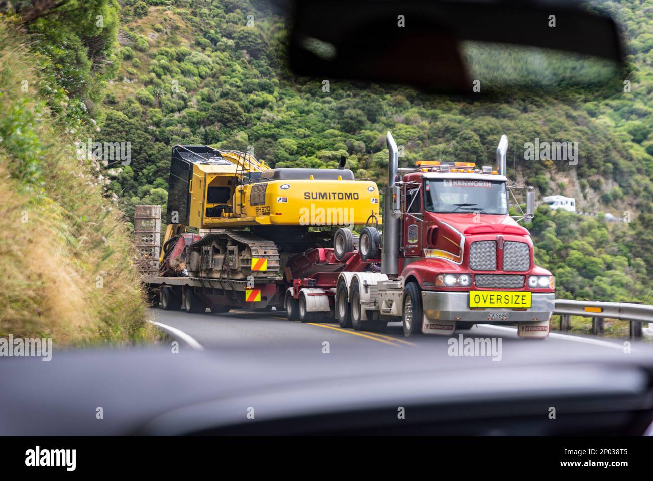 In auto, con carico di grandi dimensioni che prende entrambe le corsie di strada sul passo Remutaka, Hutt superiore, Wellington, Nuova Zelanda. Ampia ostruzione del carico Foto Stock