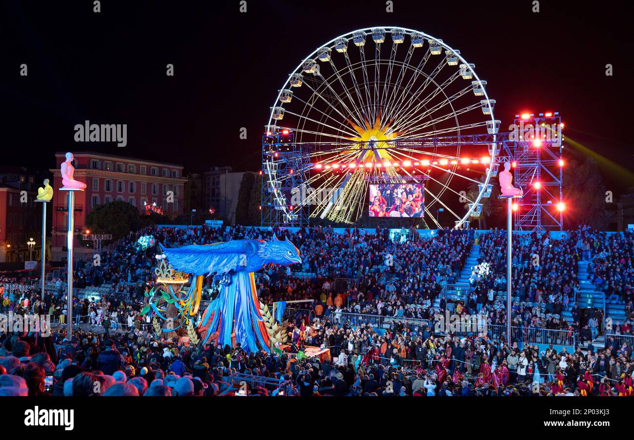 Galleggia di notte (la Fenice) alla parata annuale di luci di Carnevale 150th a Nizza. Grande ruota panoramica sullo sfondo. Foto Stock
