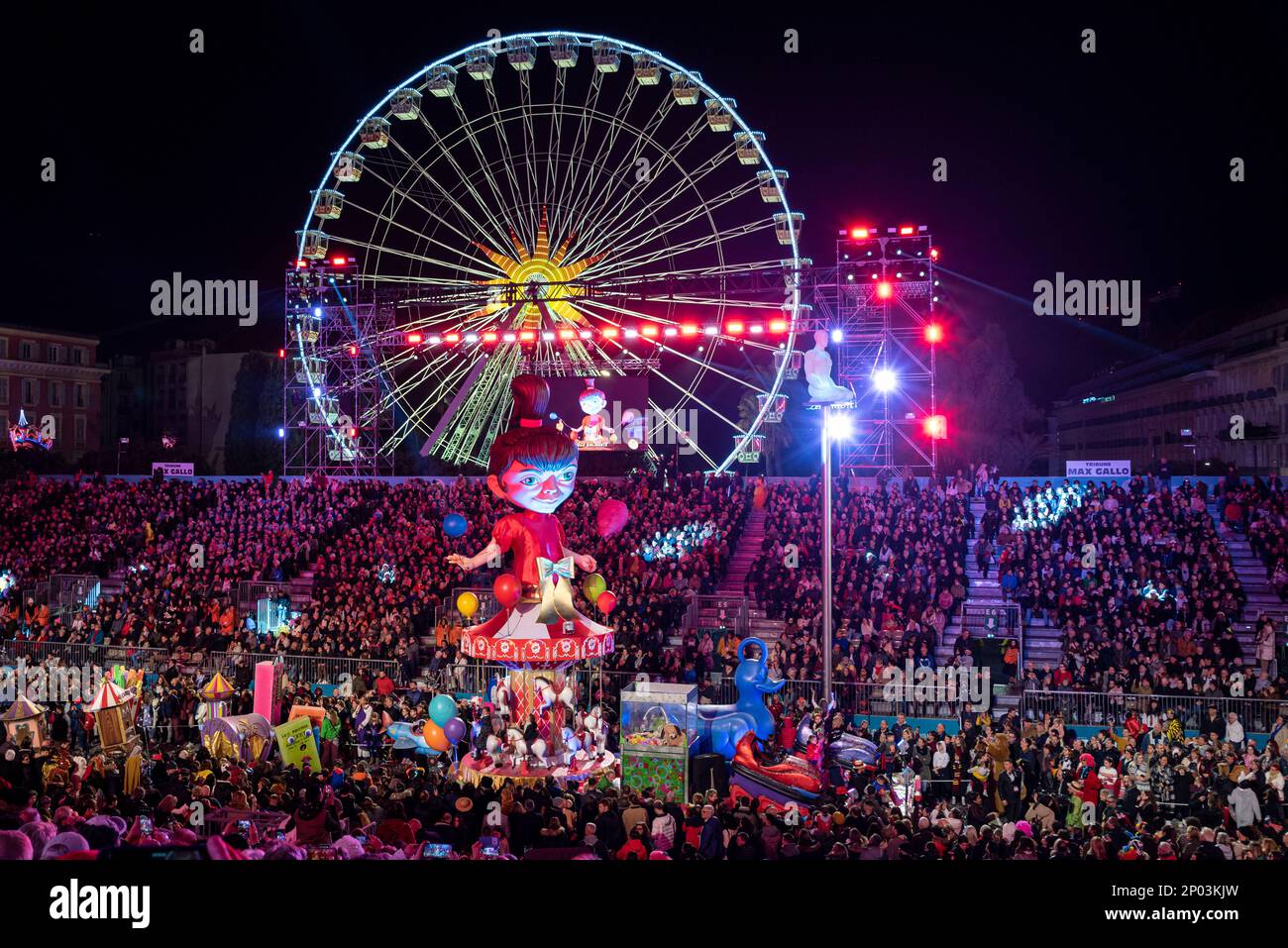 Galleggia di notte (la rotonda magica) alla 150th° sfilata annuale di luci di Carnevale a Nizza. Grande ruota panoramica sullo sfondo. Foto Stock