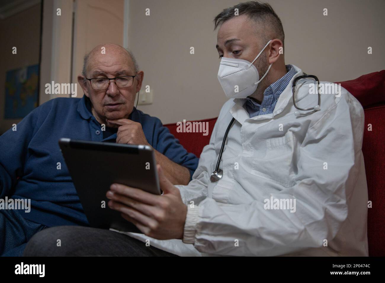 Un medico generico durante una visita a casa al suo paziente anziano. Foto Stock