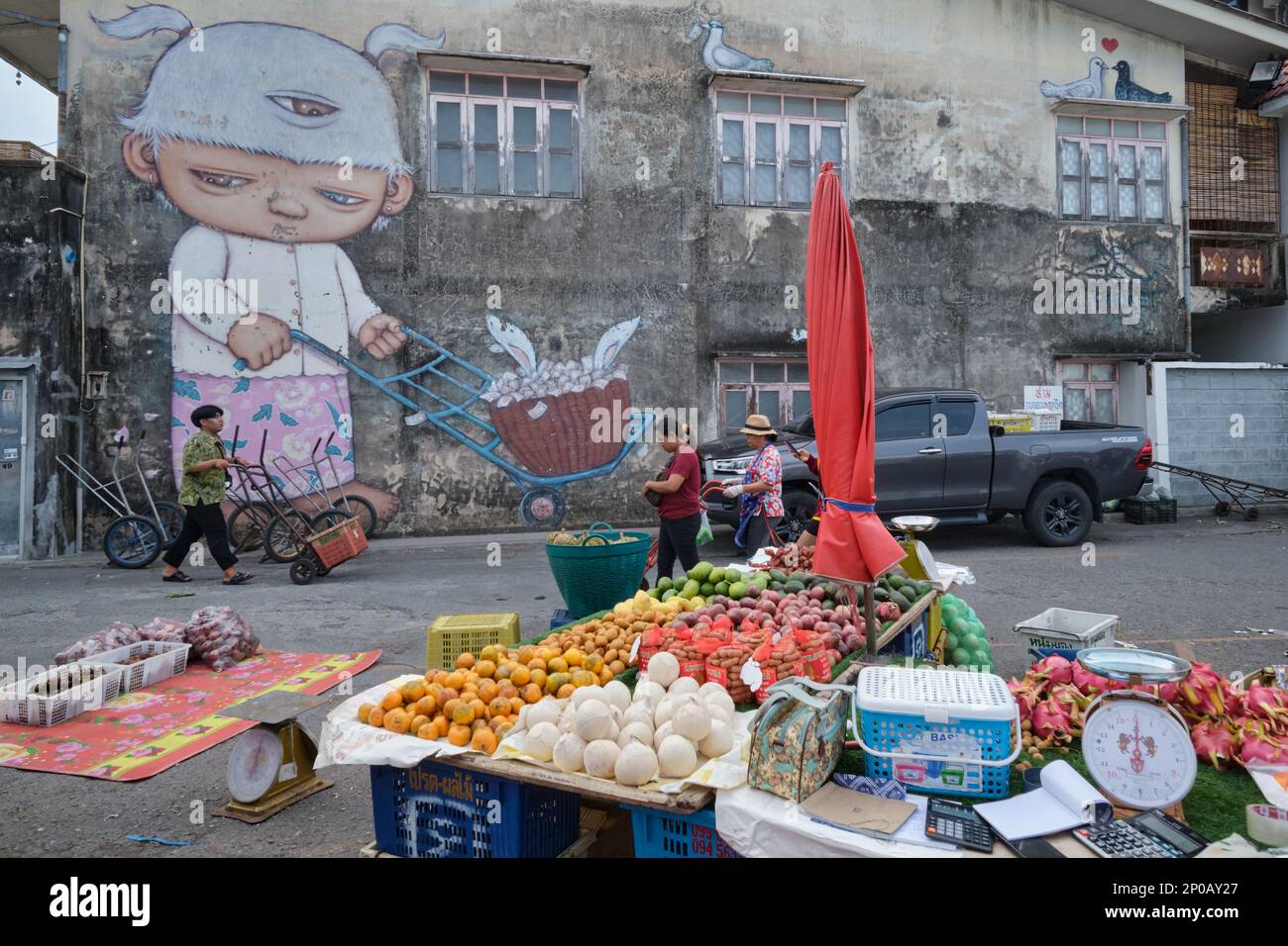 Un murale dell'artista Alex Face nel mercato umido della città di Phuket, Thailandia, che mostra il suo marchio Mardi a tre occhi che lavora come un portiere di mercato Foto Stock