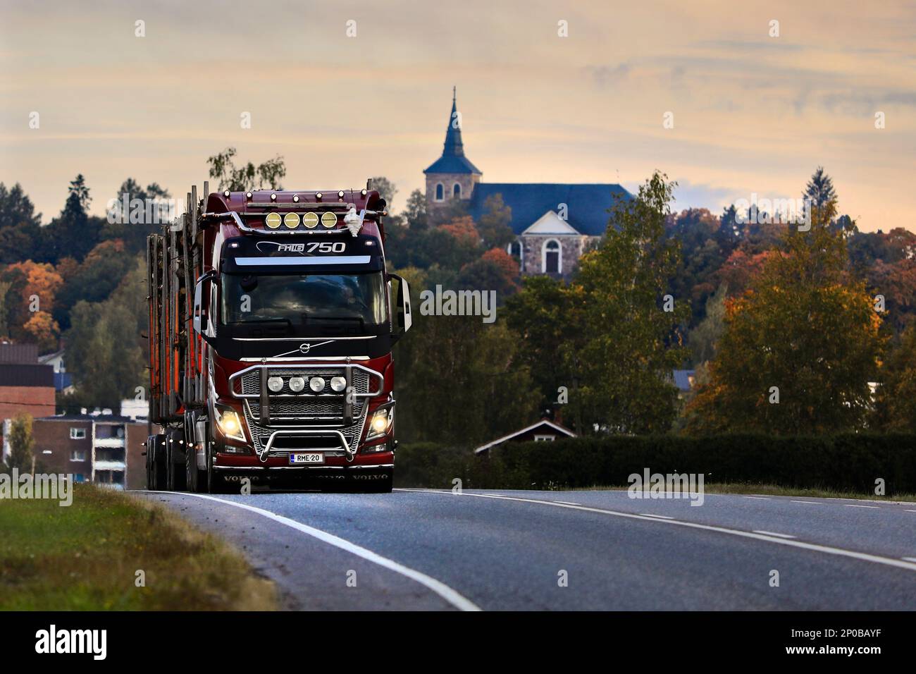 Red Volvo FH16 750 autocarro trasporto tronchi carico presto su una mattina di settembre, sullo sfondo Uskela Chiesa Salo, Finlandia. Settembre 23, 2022. Foto Stock
