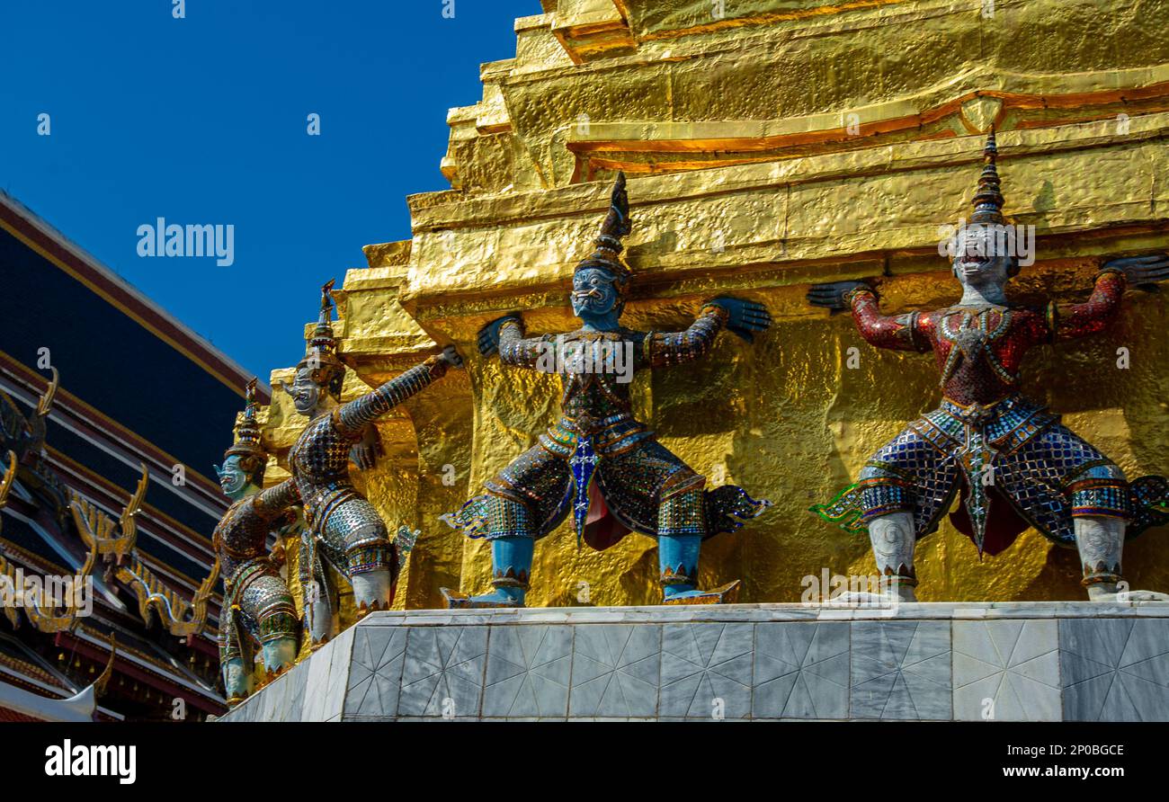 Wat Phra Kaew a Bangkok dettaglio di uno dei chedi dorati, mostrando i giganti di sostegno intorno alla base. Il colore e l'abbigliamento di queste figure ident Foto Stock