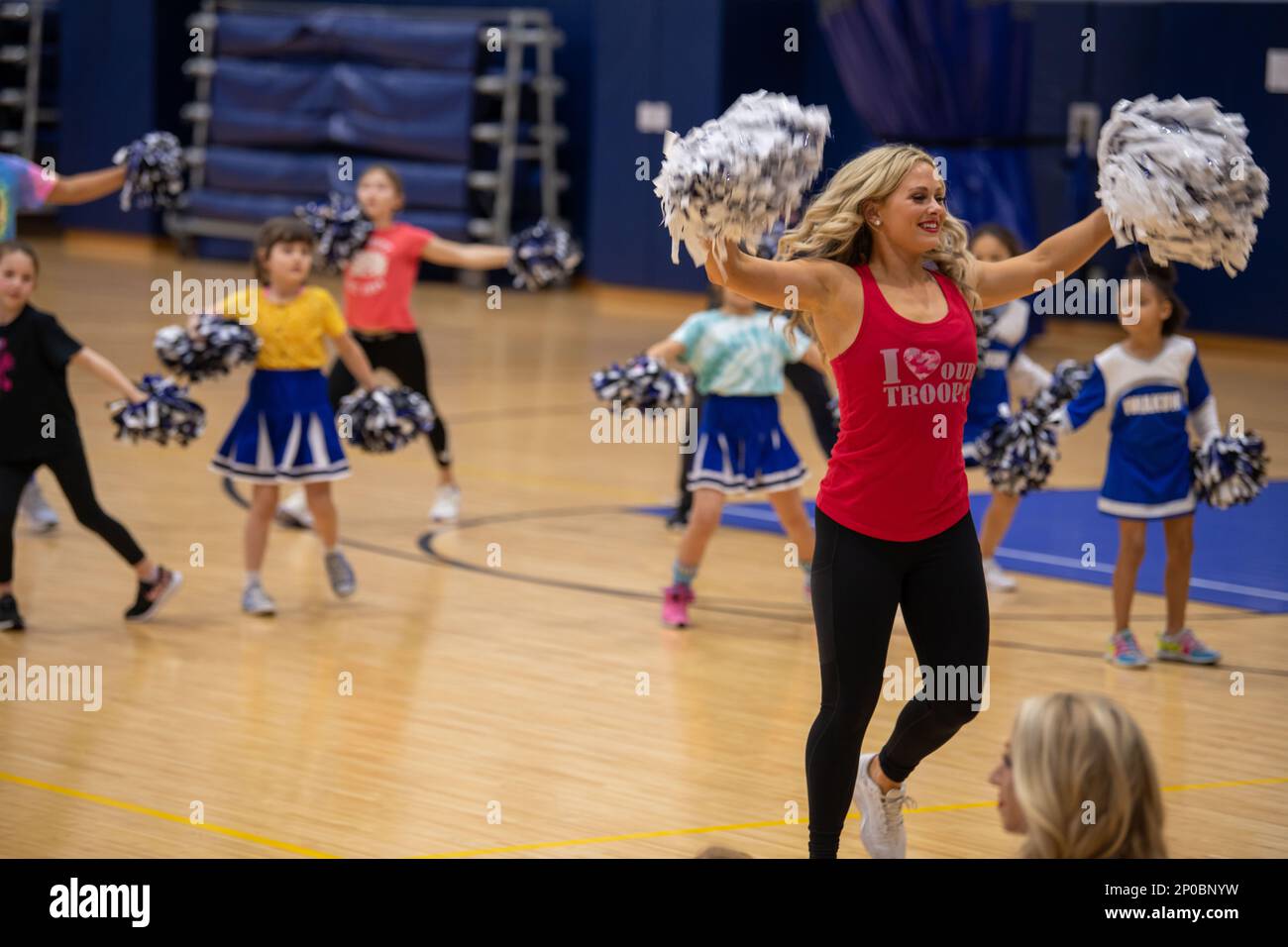 Michelle Harvey, cheerleader con i Los Angeles Rams, esegue una routine di allegria insieme ai bambini della Marine Corps Air Station Iwakuni durante la Pro Blitz Cheer Clinic su MCAS Iwakuni, Giappone, 12 febbraio 2023. Il tour Armed Forces Entertainment Pro Blitz consente ai membri del servizio e alle loro famiglie di incontrare cheerleader e giocatori della National Football League. Foto Stock