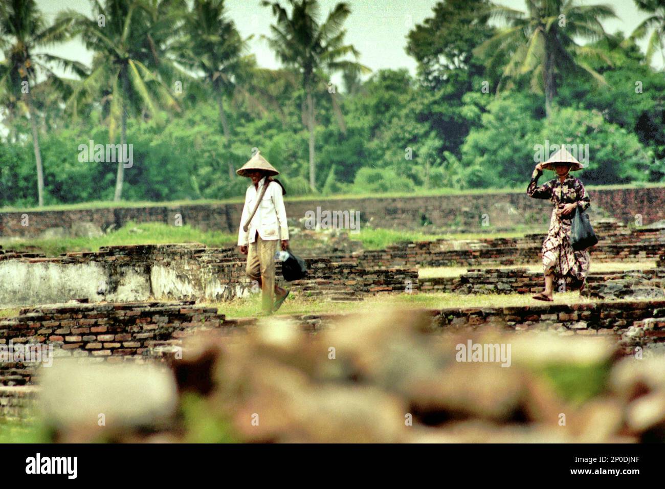 Agricoltori che camminano attraverso le rovine del Palazzo Surosowan, un patrimonio culturale del periodo Sultanato Banten situato in un'area chiamata Banten lama (Old Banten) a Serang, Banten, Indonesia, in questa foto scattata nel 2004. Una ricerca sul campo condotta recentemente da Nurikah e E. Rakhmat Jazuli (Facoltà di giurisprudenza, Sultan Ageng Tirtayasa University, Banten) ha rivelato che ci sono state molte violazioni contro il trattamento dei beni culturali nella zona. Foto Stock