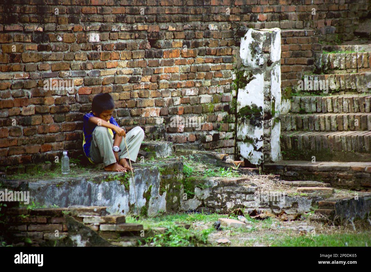 Un bambino è seduto alla rovina del Surosowan Palace, un patrimonio culturale del periodo Sultanato Banten situato in un'area chiamata Banten lama (Old Banten) a Serang, Banten, Indonesia, in questa foto scattata nel 2004. Una ricerca sul campo condotta recentemente da Nurikah e E. Rakhmat Jazuli (Facoltà di giurisprudenza, Sultan Ageng Tirtayasa University, Banten) ha rivelato che ci sono state molte violazioni contro il trattamento dei beni culturali nella zona. Foto Stock