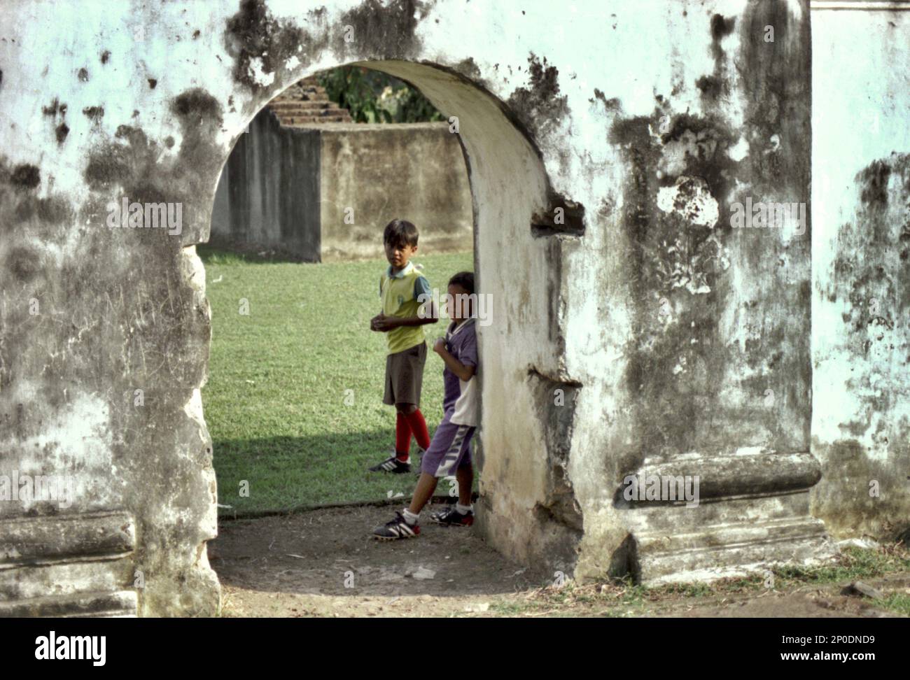 I bambini che indossano appellamenti per giocare a calcio sono visti all'ingresso di un muro alle rovine del Palazzo Kaibon, un patrimonio culturale del periodo Sultanato di Banten situato in un'area chiamata Banten lama (Old Banten) a Serang, Banten, Indonesia, in questa foto scattata nel 2004. Una ricerca sul campo condotta recentemente da Nurikah e E. Rakhmat Jazuli (Facoltà di giurisprudenza, Sultan Ageng Tirtayasa University, Banten) ha rivelato che ci sono state molte violazioni contro il trattamento dei beni culturali nella zona. La gente sta svolgendo attività sportive nell'ambiente dei beni culturali,... Foto Stock