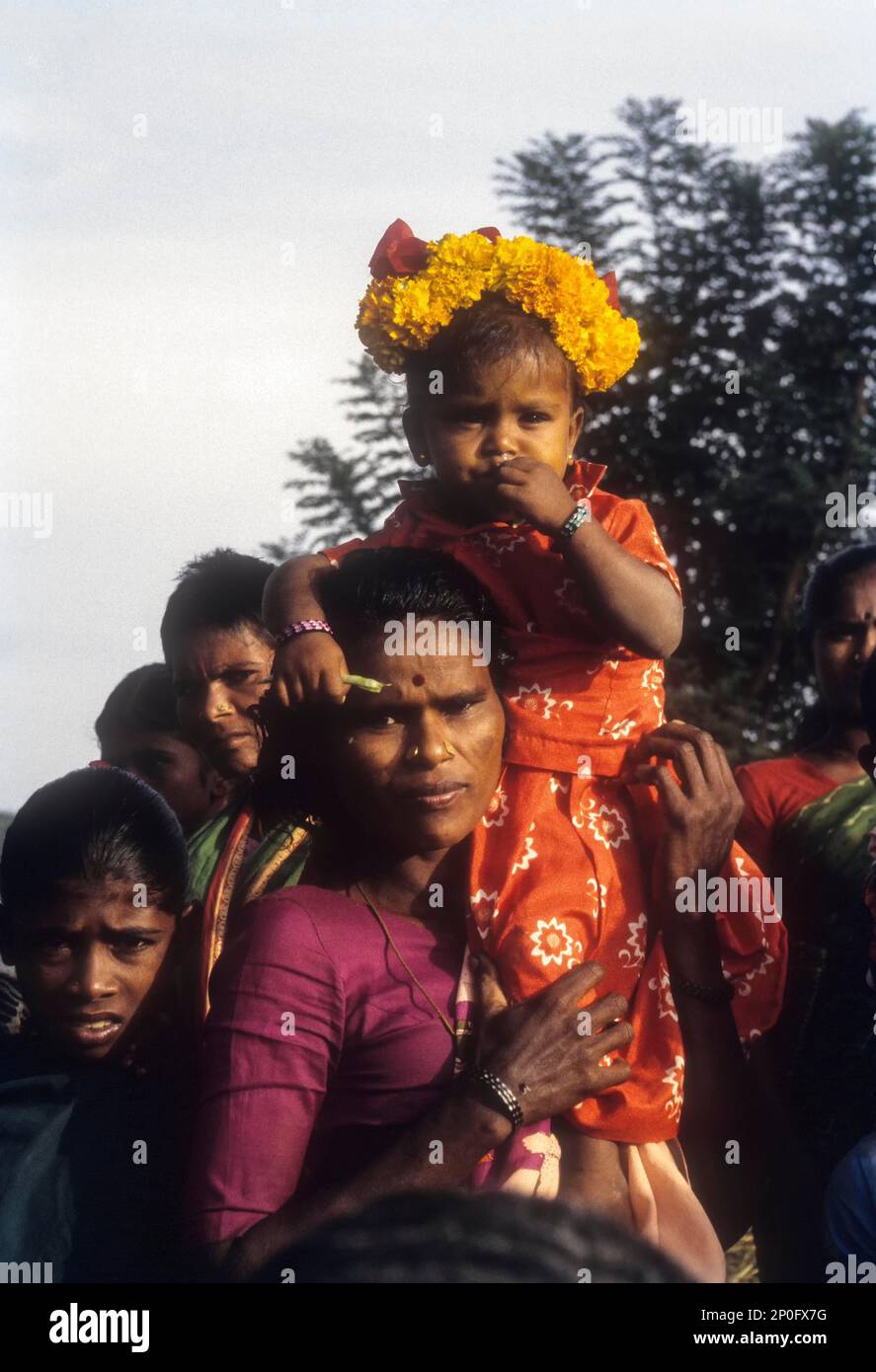 Ragazza di villaggio seduto in sicurezza, Madurai, Tamil Nadu, India. Figlia seduta sulla spalla della madre, Madurai, Tamil Nadu, India Foto Stock