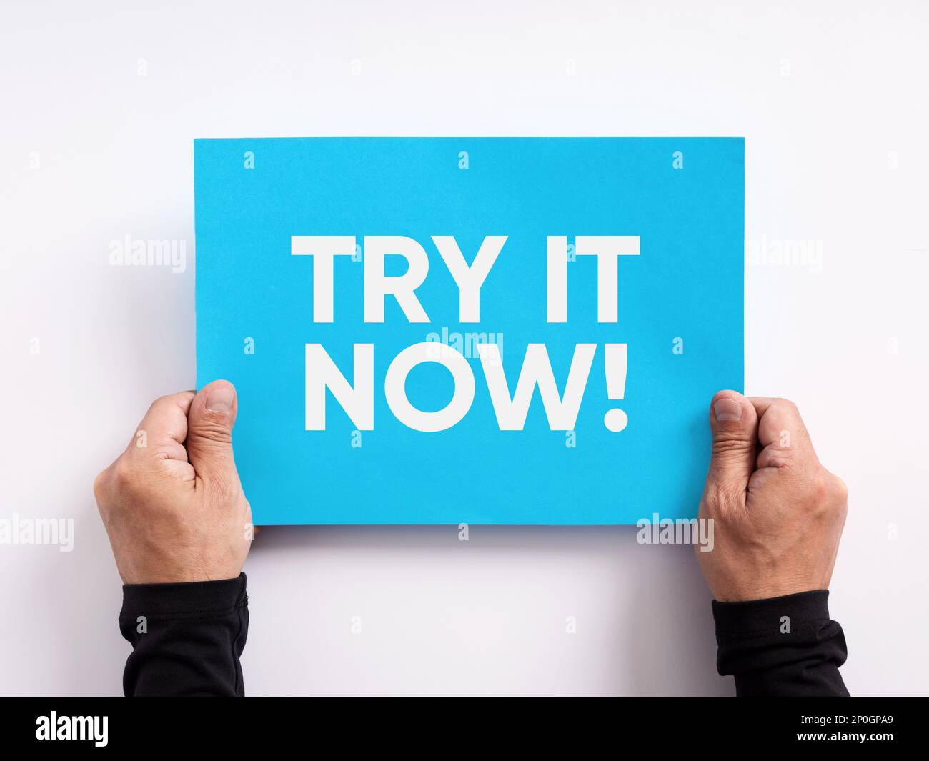 Offerta di prova del prodotto o del servizio. Mano maschio che tiene una carta blu con il messaggio di marketing aziendale provatelo ora. Foto Stock