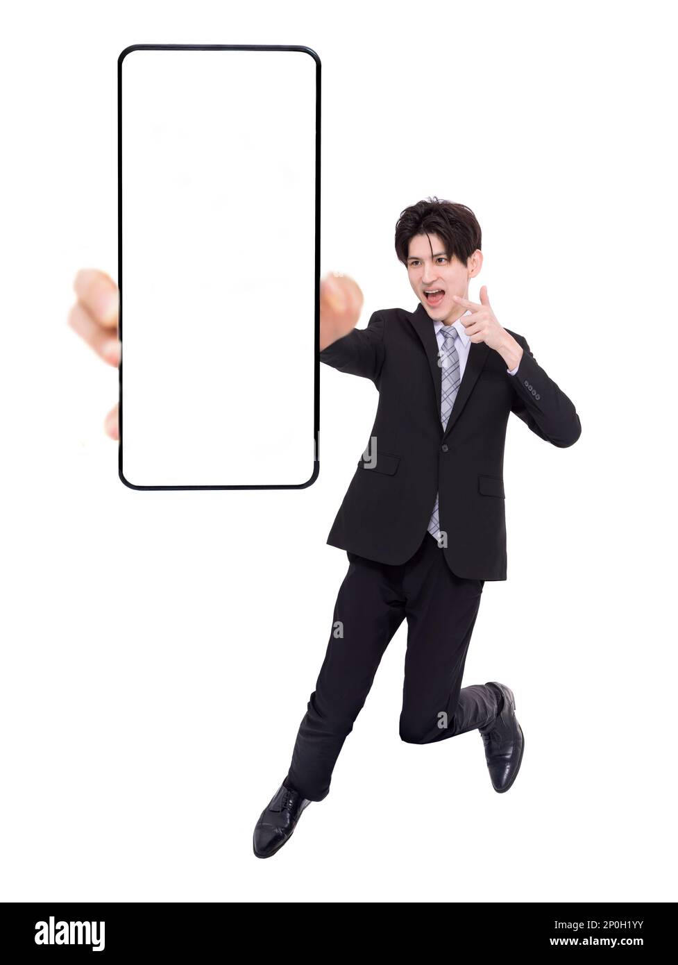 Giovane uomo d'affari che salta e mostra lo schermo vuoto del telefono cellulare Foto Stock