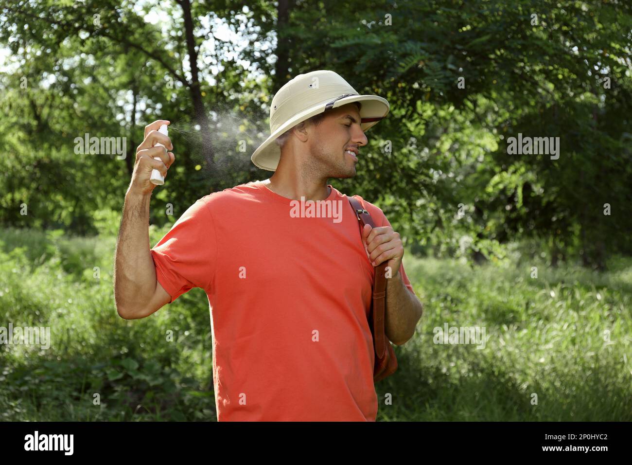 Uomo che spruzzano il repellente del tick sul collo durante l'escursione in natura Foto Stock