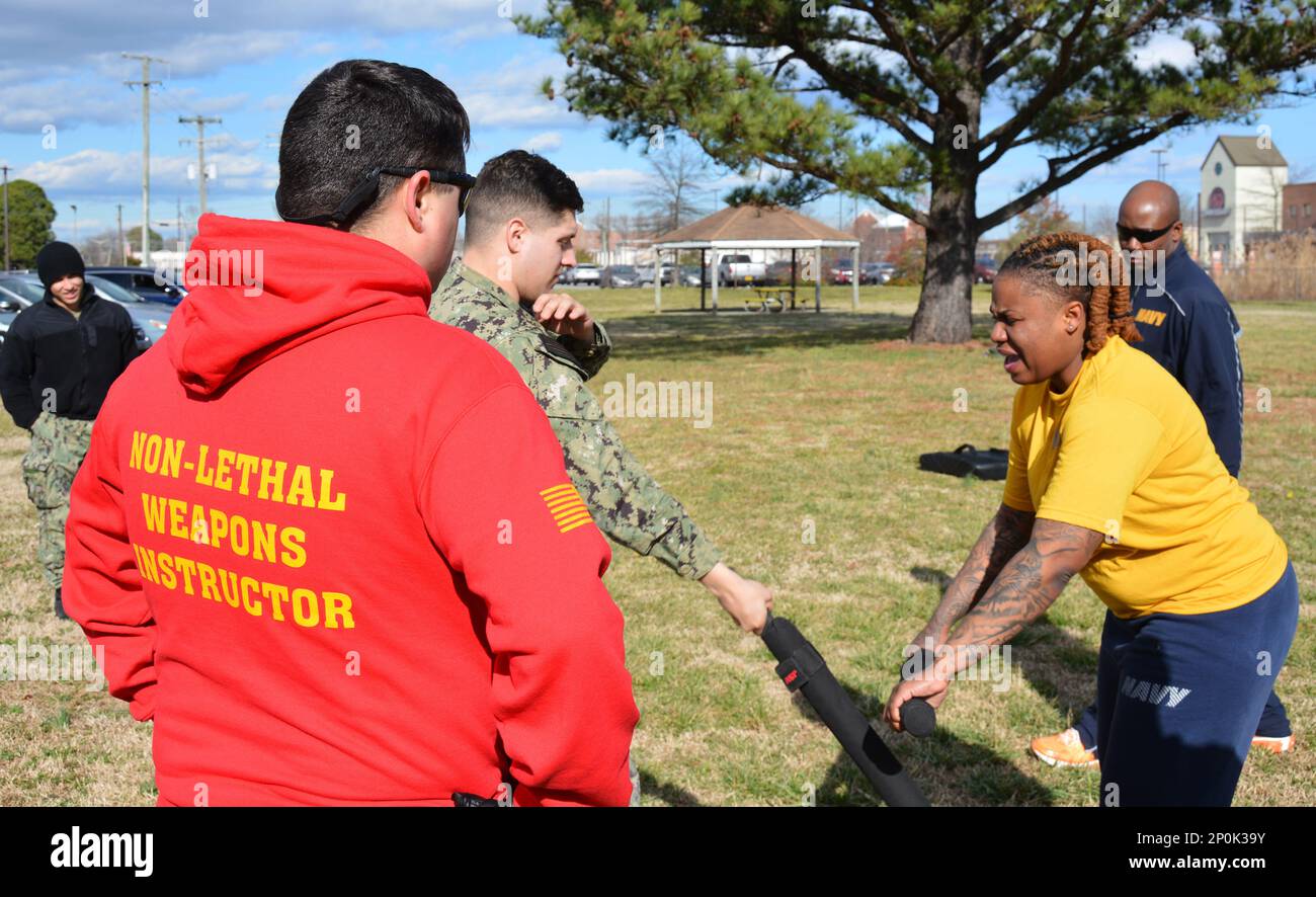 PORTSMOUTH, Virginia (20 gennaio 2023) Logisitics Specialist 2nd Class Alexis Keith (a destra) blocca un colpo di batone da Aviation Ordnance Airman Dylan Villa (al centro) dopo essere stato spruzzato con oleoresin capsicum (OC) spray durante la formazione di base della forza di reazione di sicurezza (SRF-B). SRF-B è un corso completo di due settimane che fornisce conoscenze di base per i marinai per svolgere il ruolo di sentry. Foto Stock