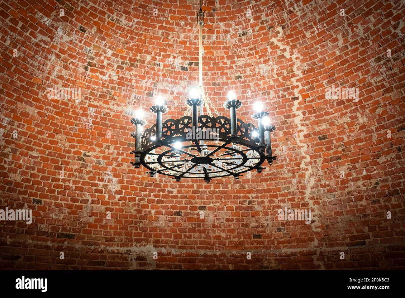 Grande lampadario d'epoca nella vecchia torre interna del Castello di Turaida. Soffitto in mattoni. Foto Stock