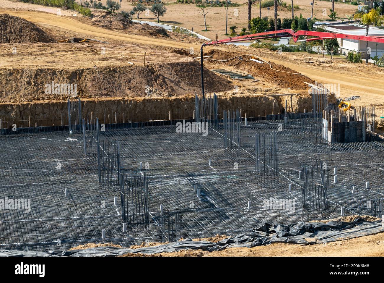 Pompa per calcestruzzo che lavora su fondazioni rinforzate in un cantiere di grandi dimensioni Foto Stock