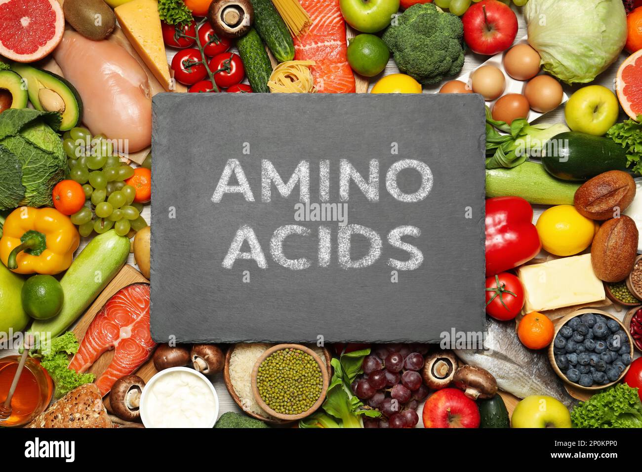 Diversi prodotti organici e ardesia tavola con testo AMINOACIDI, vista dall'alto Foto Stock