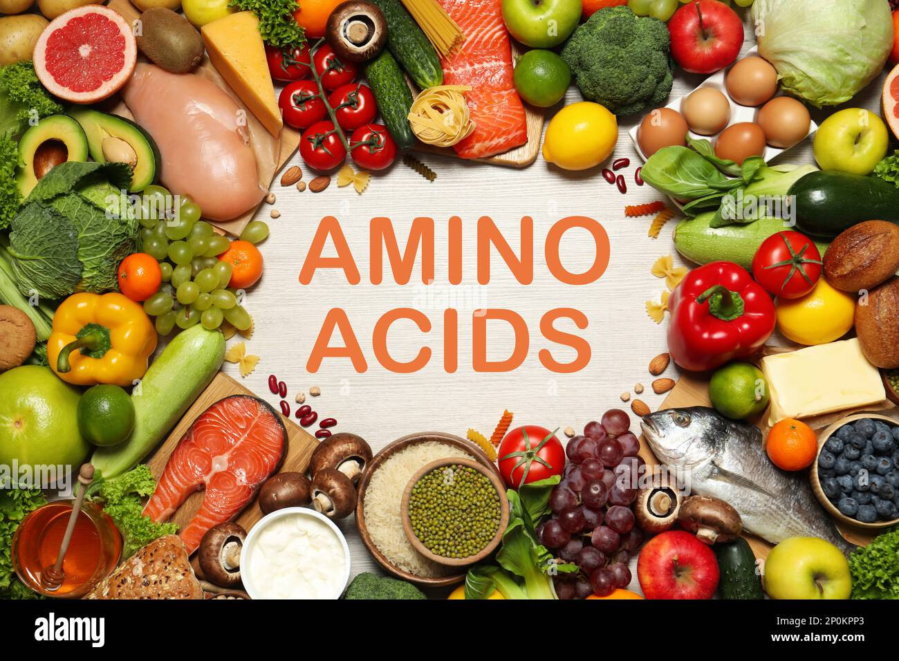 Diversi alimenti naturali su tavolo di legno bianco, piatto. Fonti di amminoacidi essenziali Foto Stock