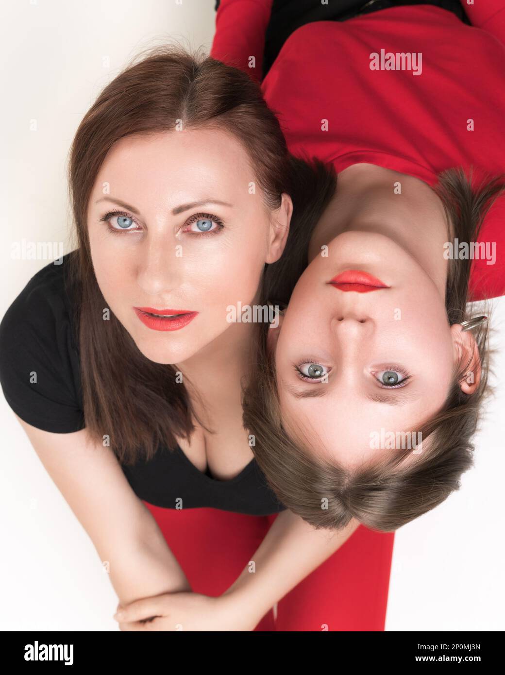 Colpo ad angolo alto di madre e figlia adolescente seduti con le spalle l'una all'altra, mettere la testa sulle spalle dell'altro. Entrambe le femmine lookin Foto Stock