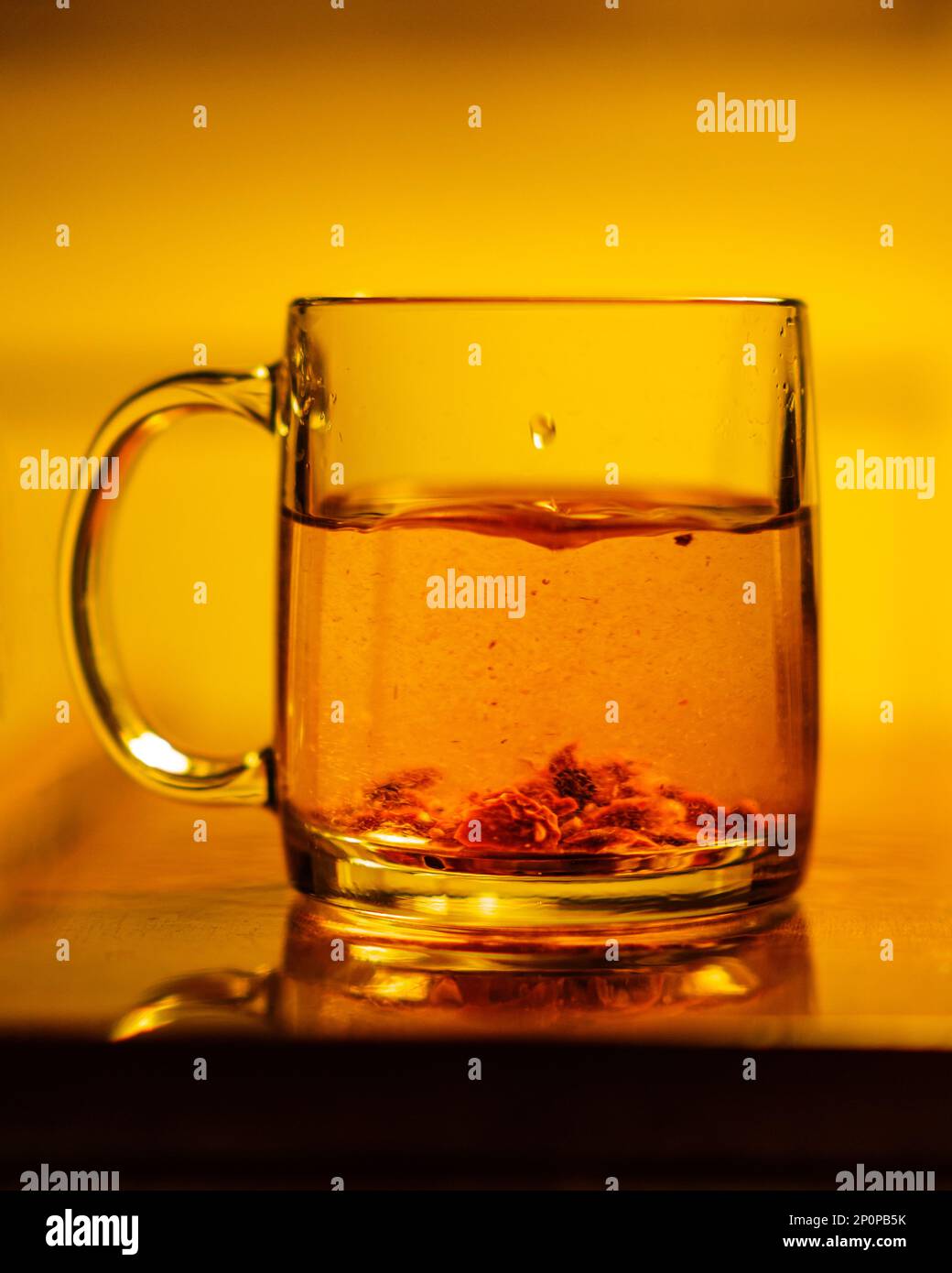 Una tazza di vetro con tè alle erbe su un tavolo. Luce calda al tungsteno. Foto Stock