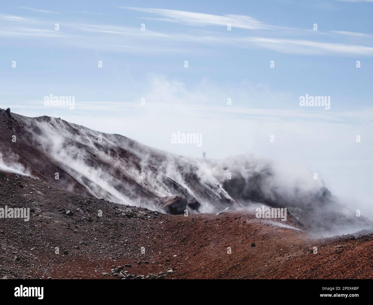 Silhouette di uomo trekking alla coldera di Avachinsky stratovulcano, noto anche come vulcano Avacha. Il turista del Backpacker si muove sulle rocce dietro il vapore Foto Stock
