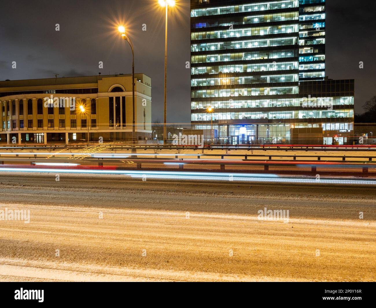 luce dal passaggio di auto su strade innevate della città nella notte d'inverno Foto Stock