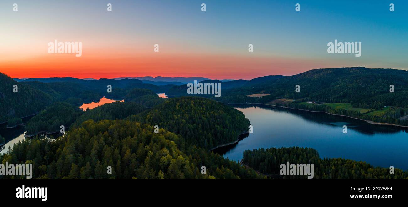 Questa immagine mozzafiato mostra uno splendido tramonto su una catena montuosa, con i raggi dorati del sole che si riflettono in un tranquillo lago sottostante Foto Stock