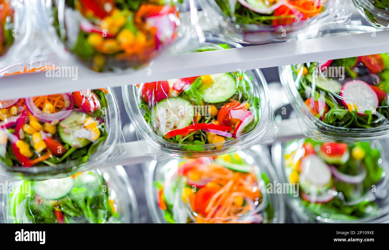 Scatole di plastica con insalate vegetali preconfezionate, messe in vendita in un frigorifero commerciale Foto Stock