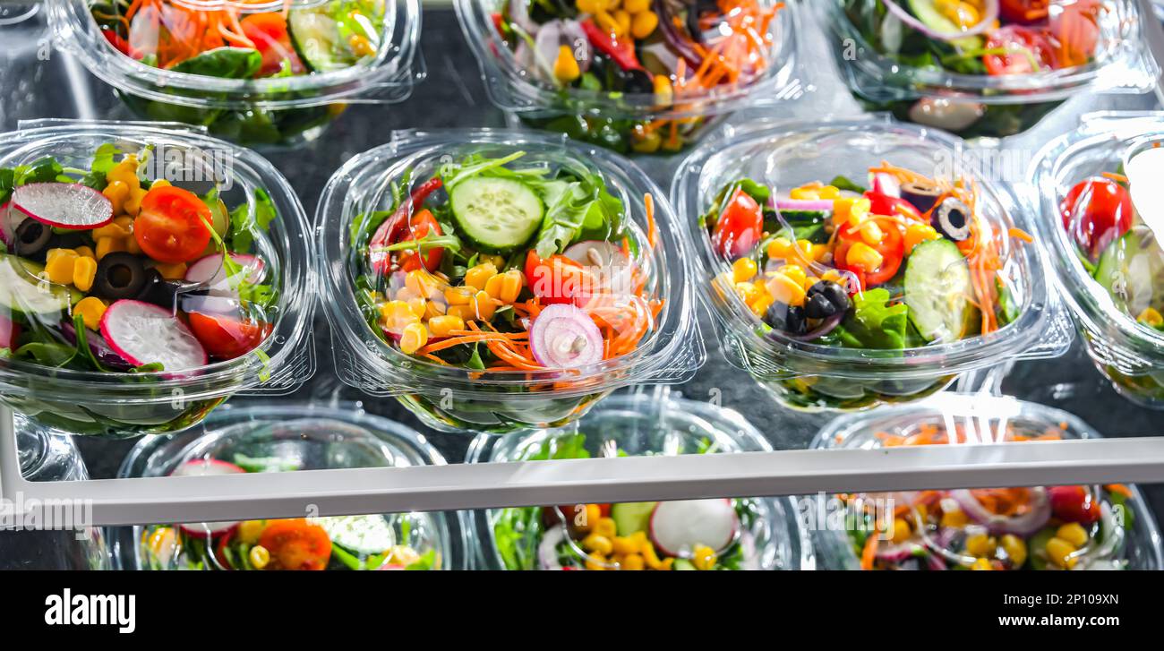 Scatole di plastica con insalate vegetali preconfezionate, messe in vendita in un frigorifero commerciale Foto Stock