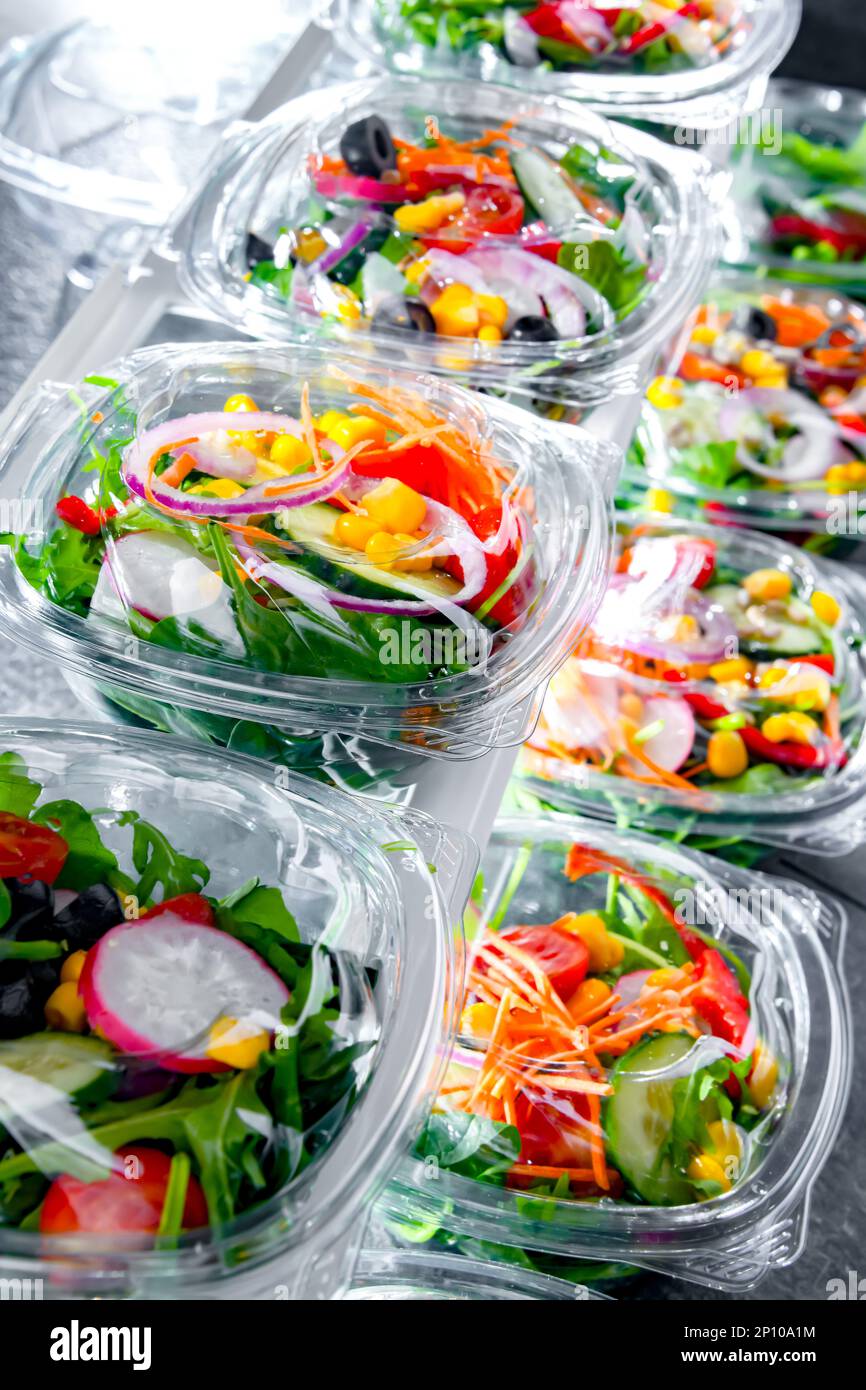 Scatole di plastica con insalate vegetali preconfezionate, messe in vendita in un frigorifero commerciale Foto Stock