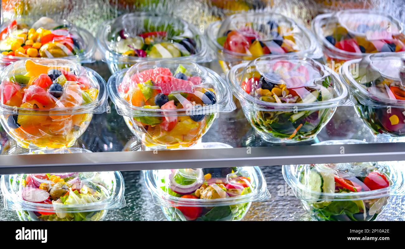 Scatole di plastica con insalate di frutta e verdura preconfezionate, messe in vendita in un frigorifero commerciale Foto Stock