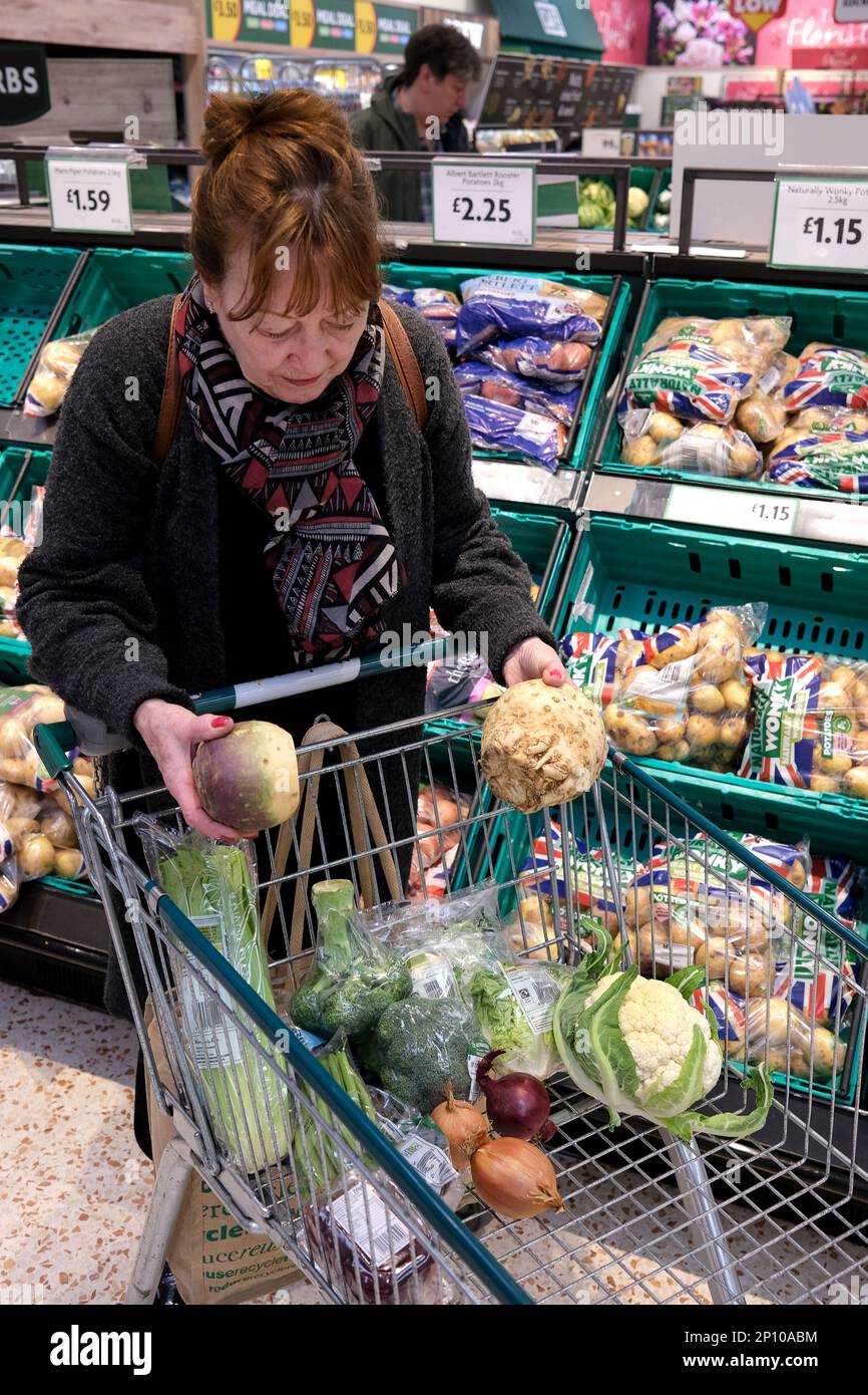 Shopping di ortaggi a radice nel supermercato Morrison, Gran Bretagna, Regno Unito. Negozio di verdure fresche shopper donna madre rivenditore al dettaglio Foto Stock