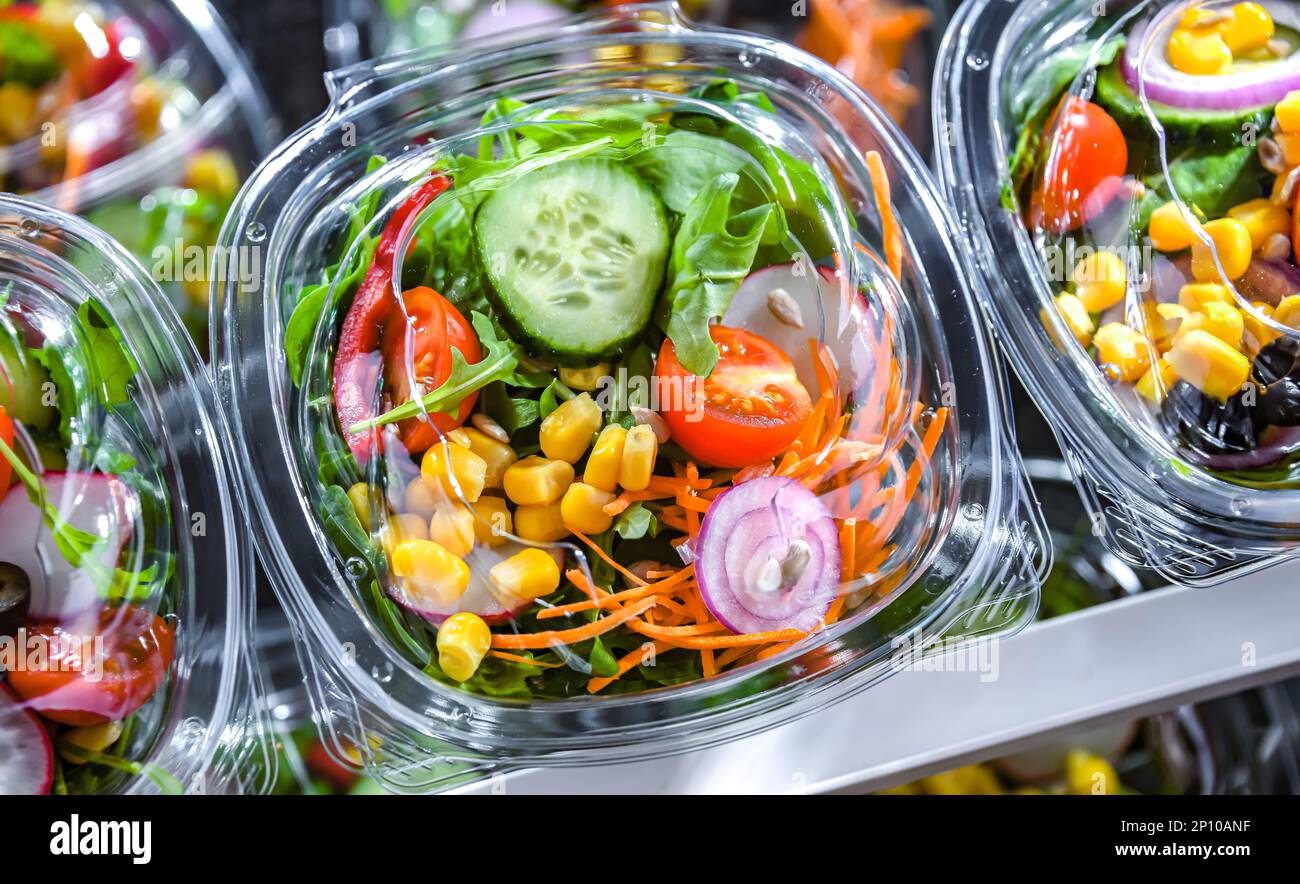 Scatole di plastica con insalate vegetali preconfezionate, messe in vendita in un frigorifero commerciale Foto Stock