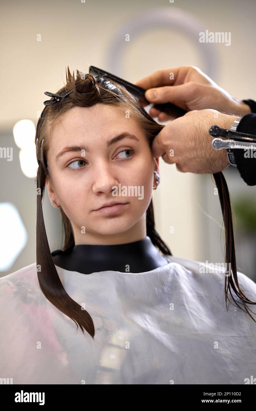 il parrucchiere maschile sta pettinando i capelli della cliente femminile. Foto Stock
