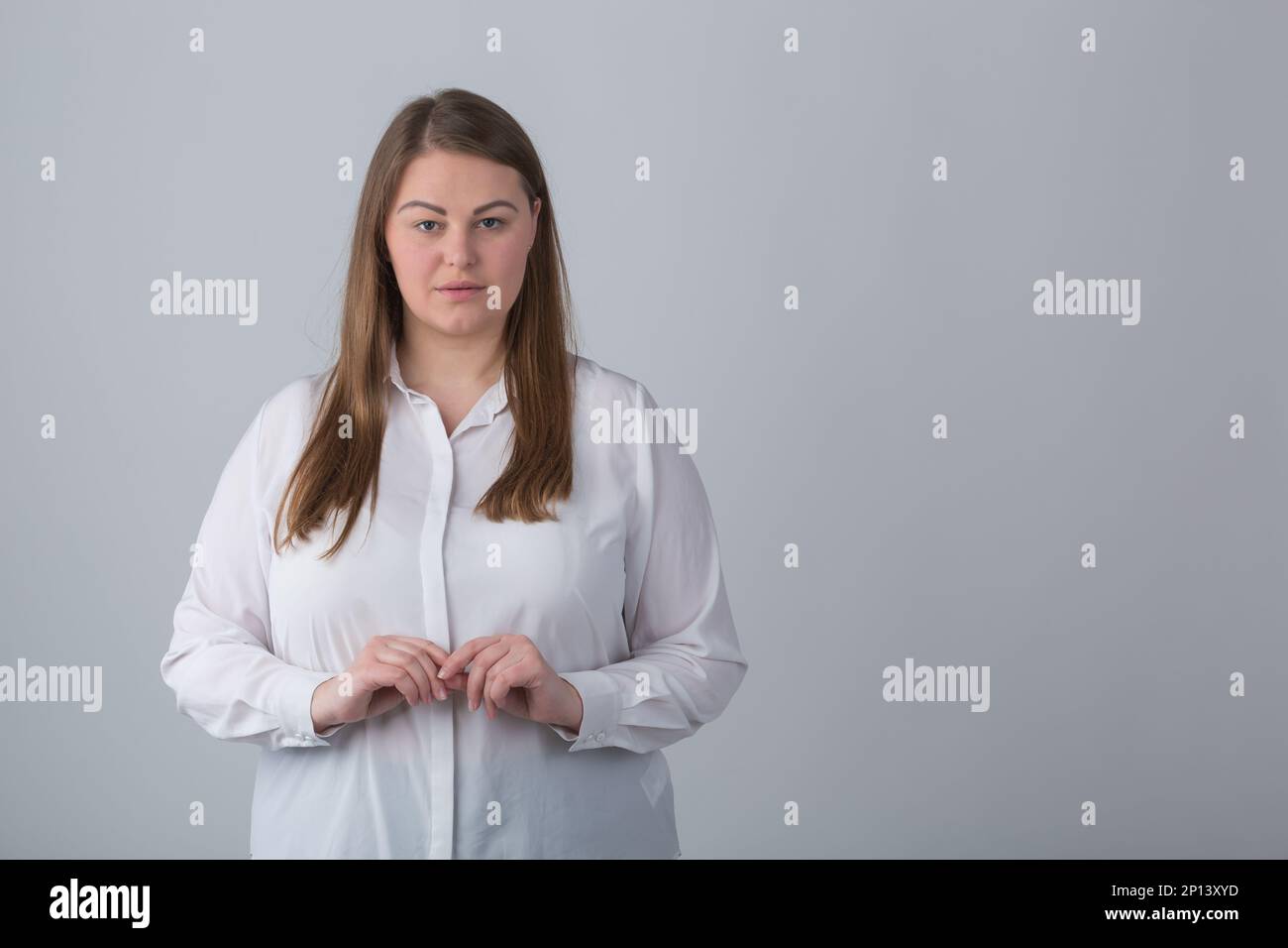 Modello in più con camicia bianca classica in studio. Ritratto di buona donna in sovrappeso con capelli lunghi Foto Stock
