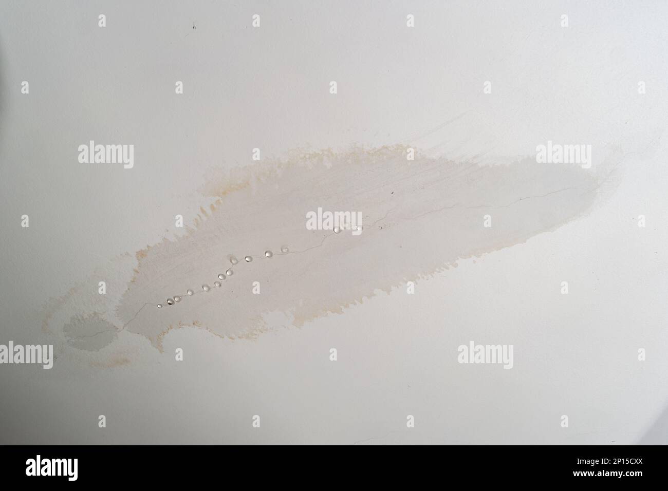 Umidità del tetto che perde nelle pareti del soffitto della camera da letto. Formazione di goccioline d'acqua e gocciolamento dal soffitto umido a seguito di allagamento di acqua piovana. Foto ravvicinata, nessuna persona. Foto Stock