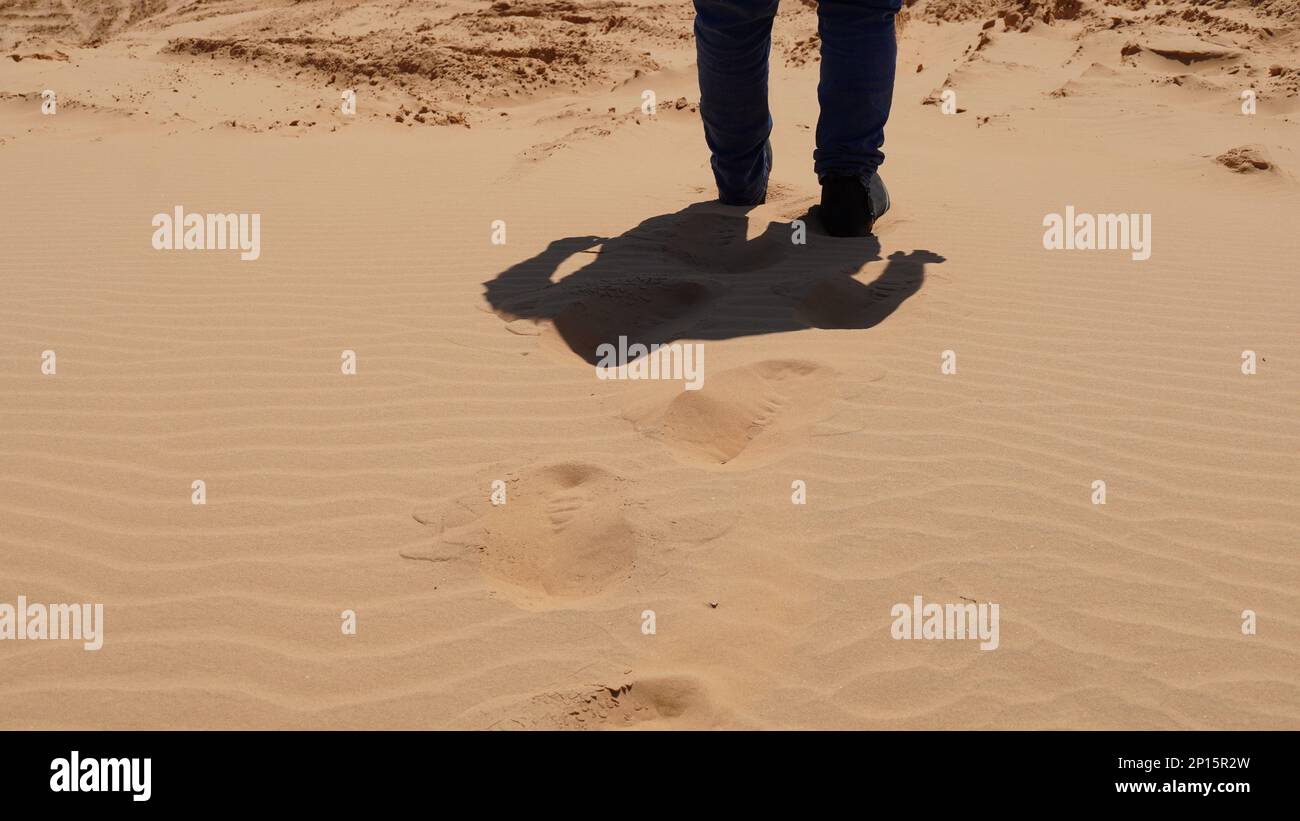 Particolare della gamba dell'uomo che cammina su una duna di sabbia Foto Stock