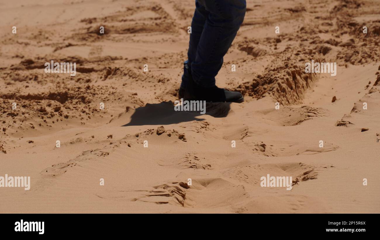 Particolare della gamba dell'uomo che cammina su una duna di sabbia Foto Stock
