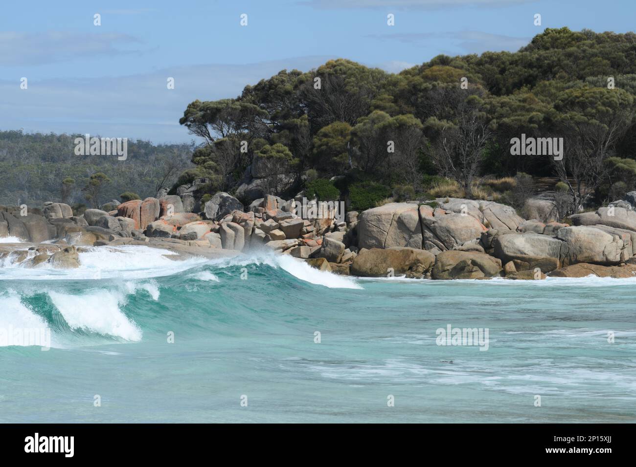 La spiaggia e i massi circostanti sono evidenziati su un mare blu con sabbia bianca e rocce scolpite Foto Stock