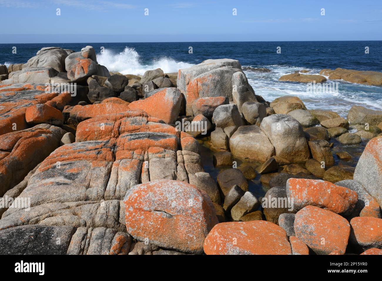 La spiaggia e i massi circostanti sono evidenziati su un mare blu con sabbia bianca e rocce scolpite Foto Stock