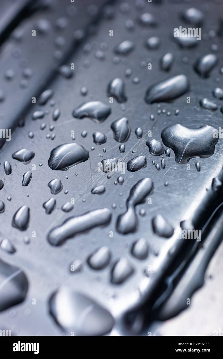 Grandi goccioline d'acqua accumulate sul primo piano del dispersore macro in metallo inossidabile di tinta blu. Foto Stock